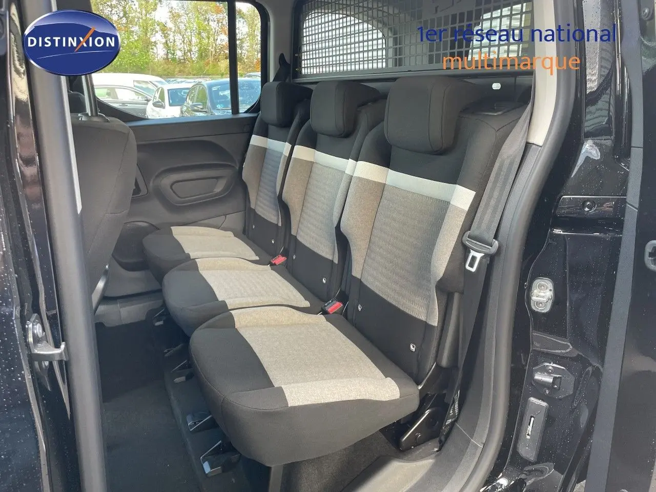 Vue latérale droite sur l'intérieur arrière du Citroën Berlingo noir, montrant les trois sièges tissu gris et noir.