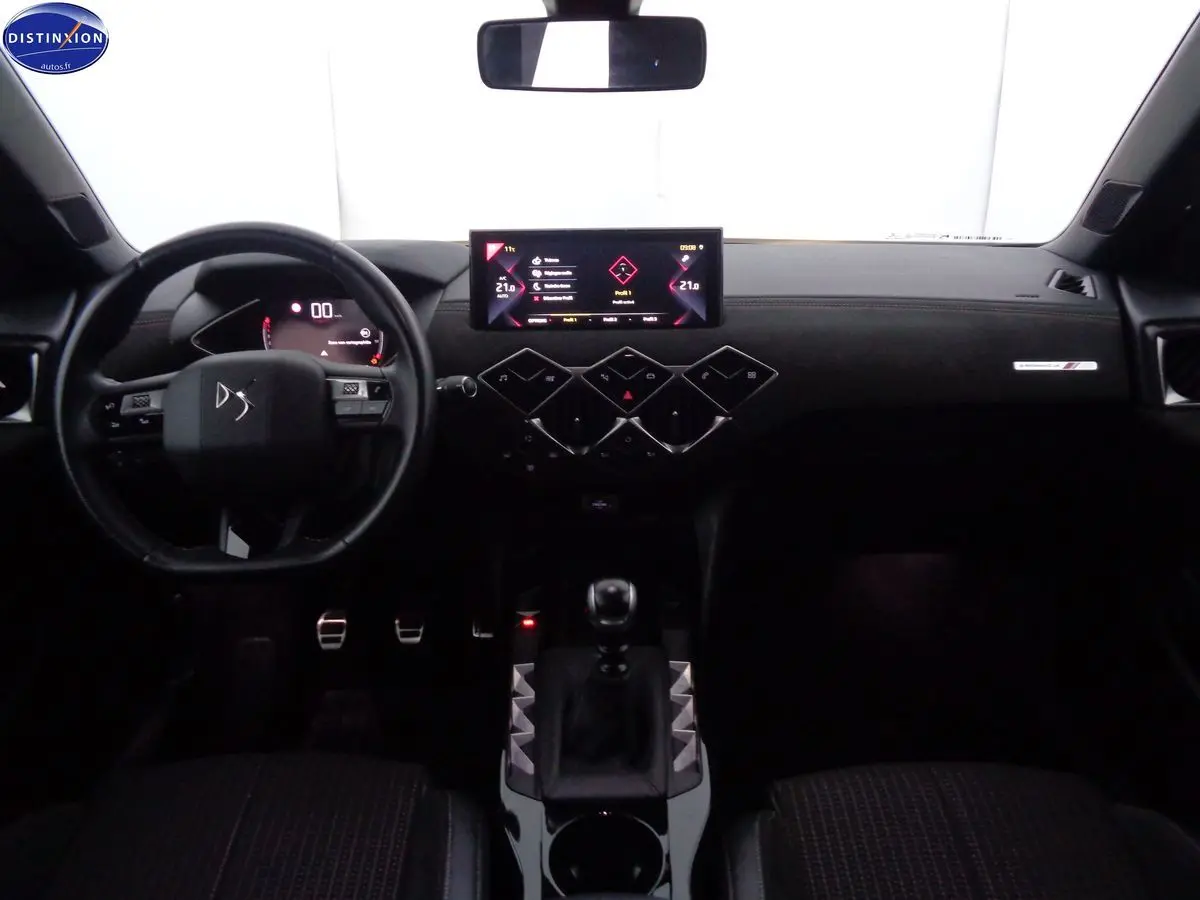 Vue intérieure avant du tableau de bord du DS3 Crossback blanc banquise, avec écran tactile et levier de vitesse manuel.