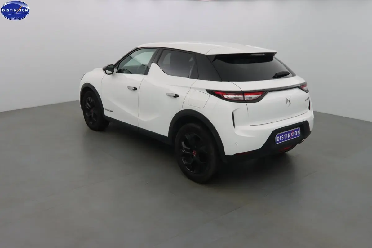 Vue 3/4 arrière droite d'un DS3 Crossback blanc banquise avec jantes noires et toit contrasté noir.