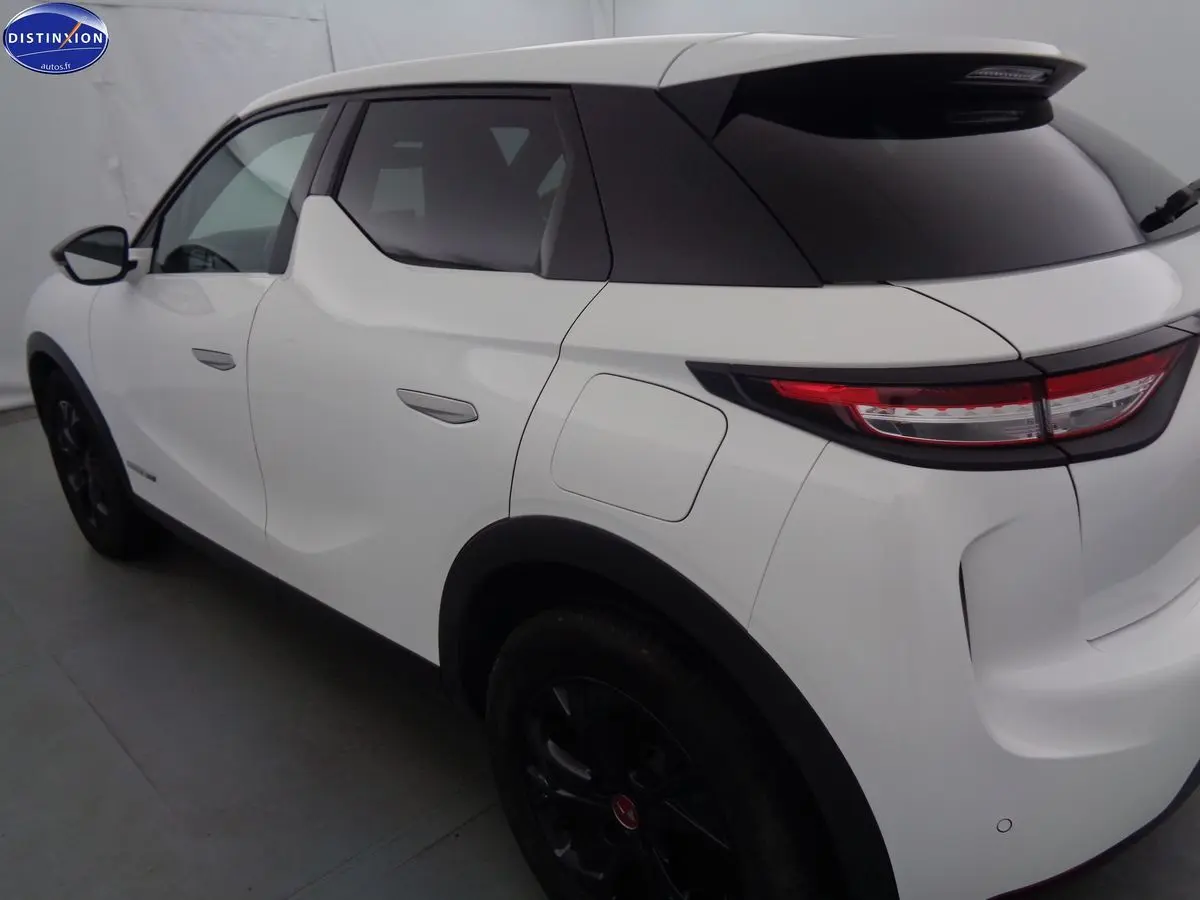 Vue 3/4 arrière droite d'un DS3 Crossback blanc banquise avec toit noir et jantes noires.