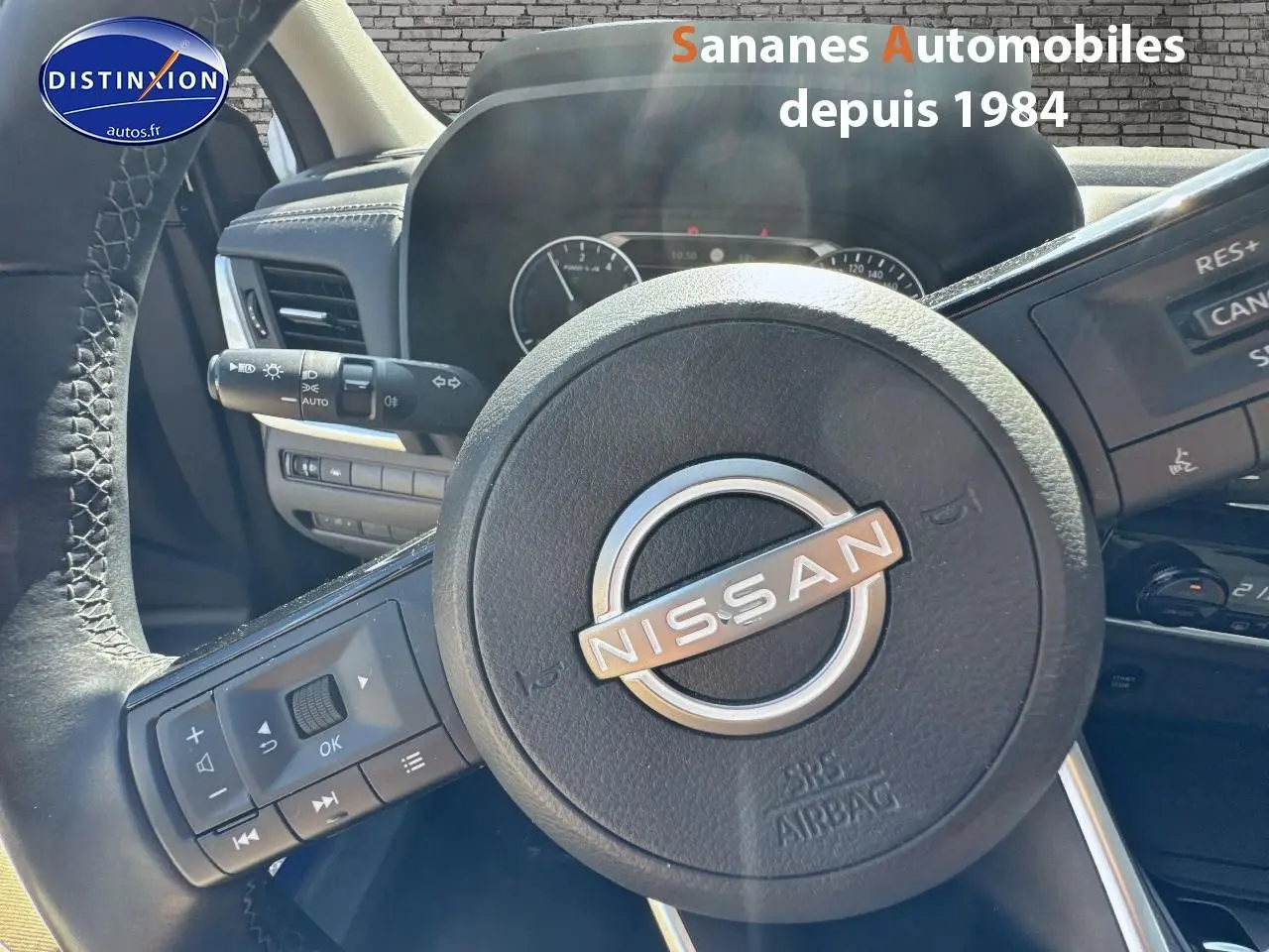 Vue rapprochée du volant Nissan du Qashqai 2023, avec commandes intégrées et tableau de bord en arrière-plan.