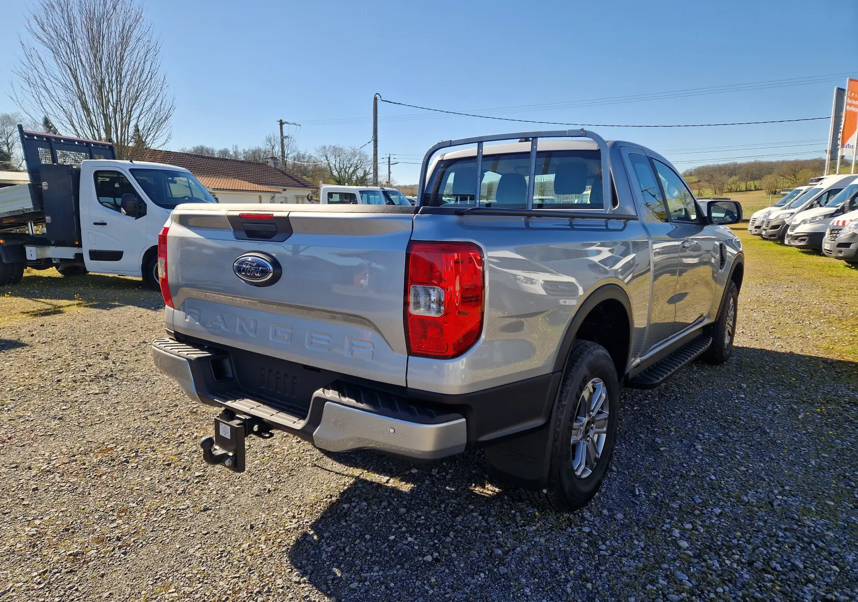 Vue 3/4 arrière droite d’un Ford Ranger Super Cabine gris Iconic avec attelage et barre de protection sur la benne.