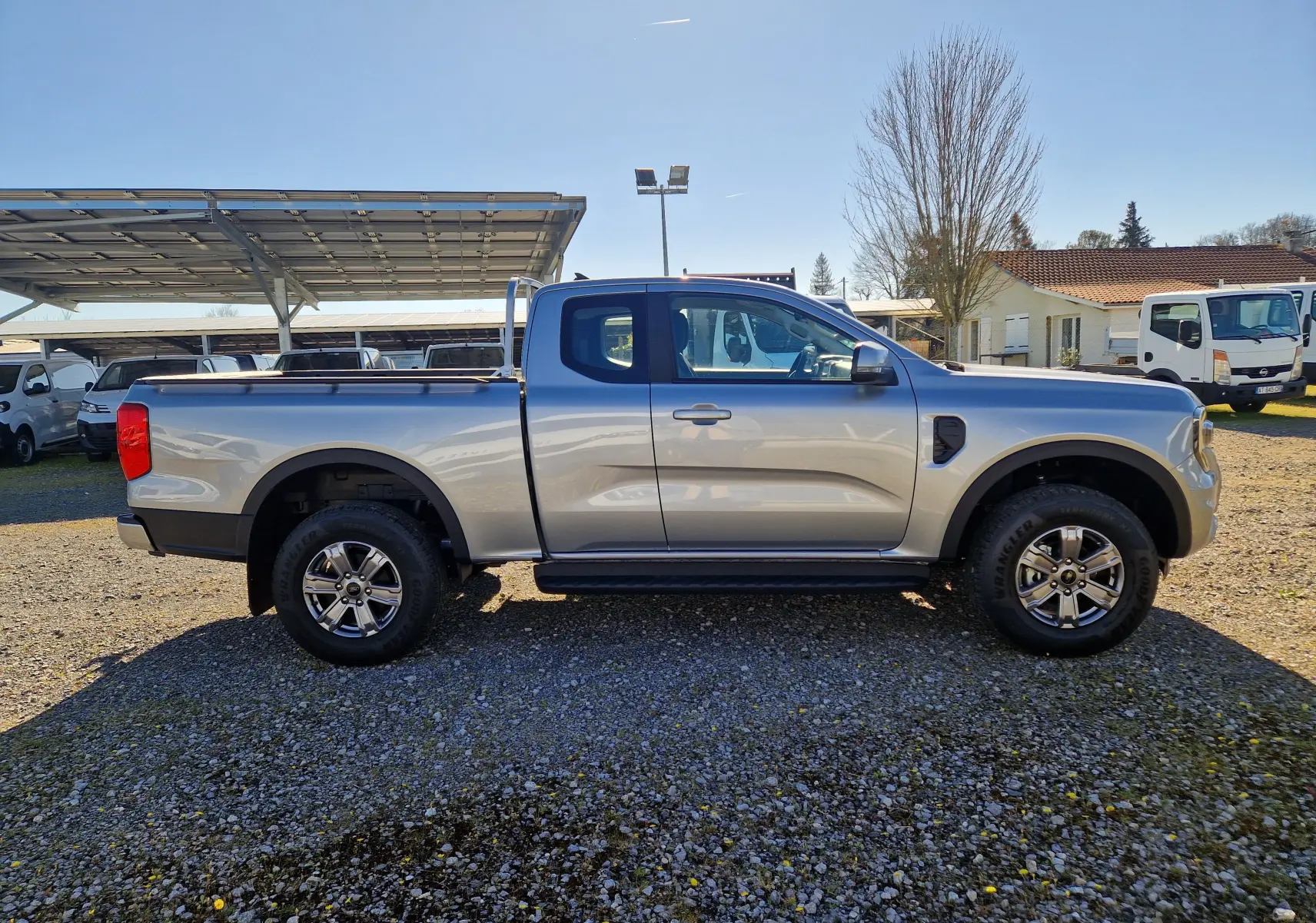 Vue de profil côté gauche d'un Ford Ranger Super Cabine gris Iconic 2026 avec benne et jantes alliage 17 pouces.