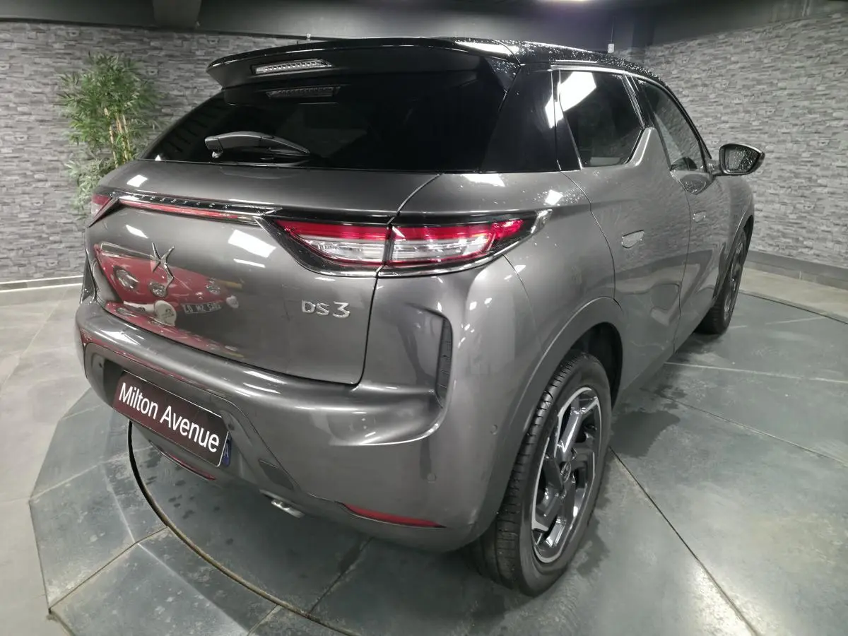 Vue 3/4 arrière droite d'un DS3 Crossback gris métallisé avec toit noir et jantes alliage 18 pouces.