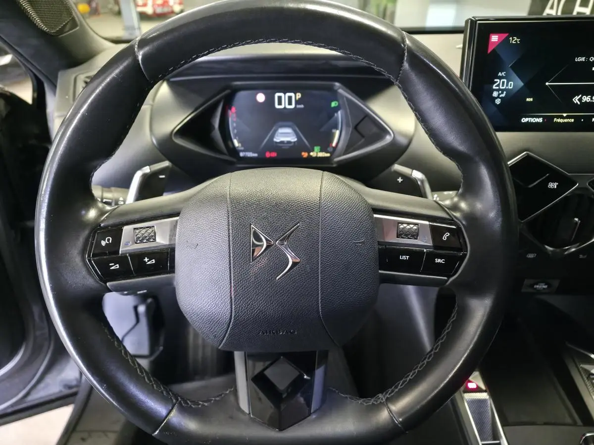 Vue rapprochée du volant en cuir noir du DS3 Crossback 2022 avec tableau de bord numérique et écran tactile central.