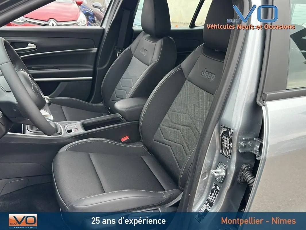 Intérieur du Jeep Avenger gris foncé, vue côté gauche sur les sièges avant en tissu et cuir avec logo Jeep brodé.