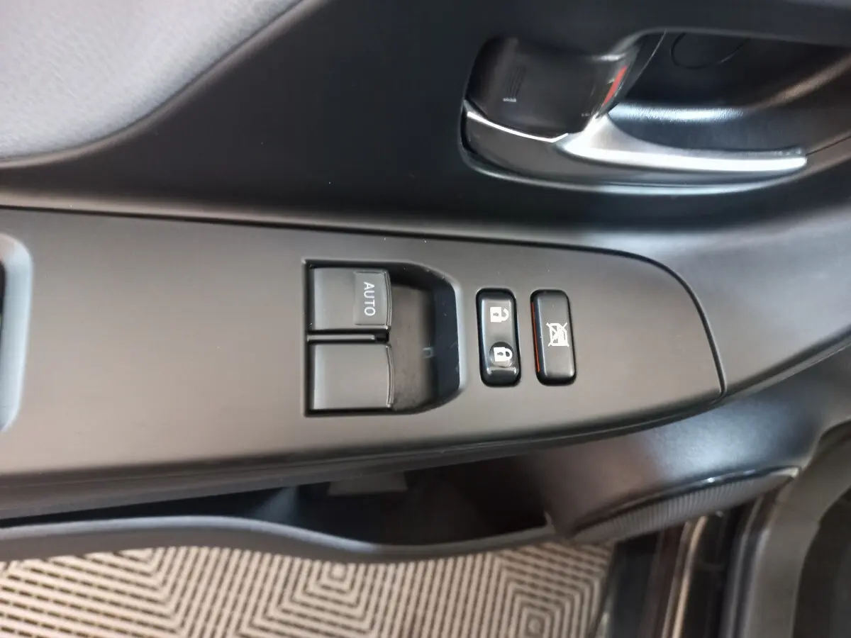 Gros plan sur les commandes de lève-vitres et verrouillage côté conducteur d'une Toyota Yaris noire de 2018.