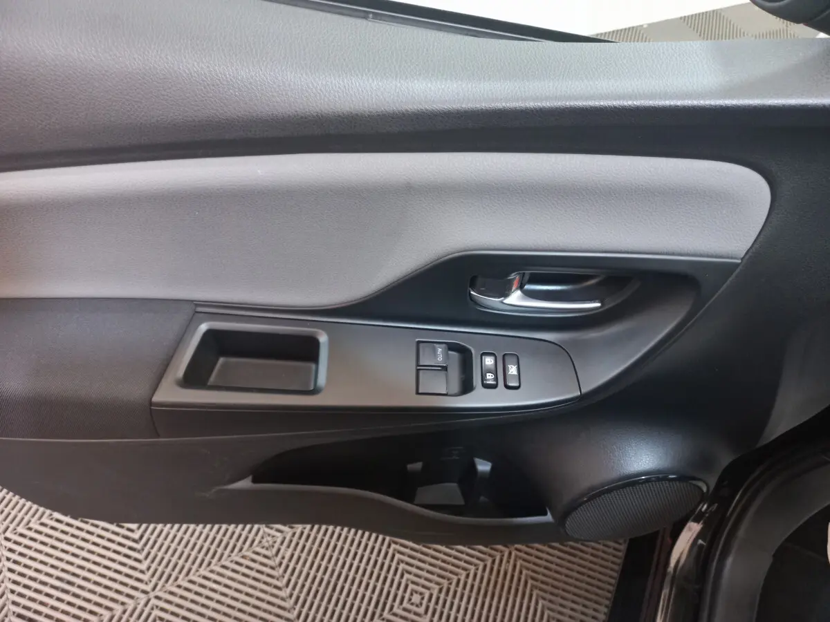 Vue rapprochée de la porte avant gauche noire de la Toyota Yaris 2018 avec commandes de vitres et poignée chrome.