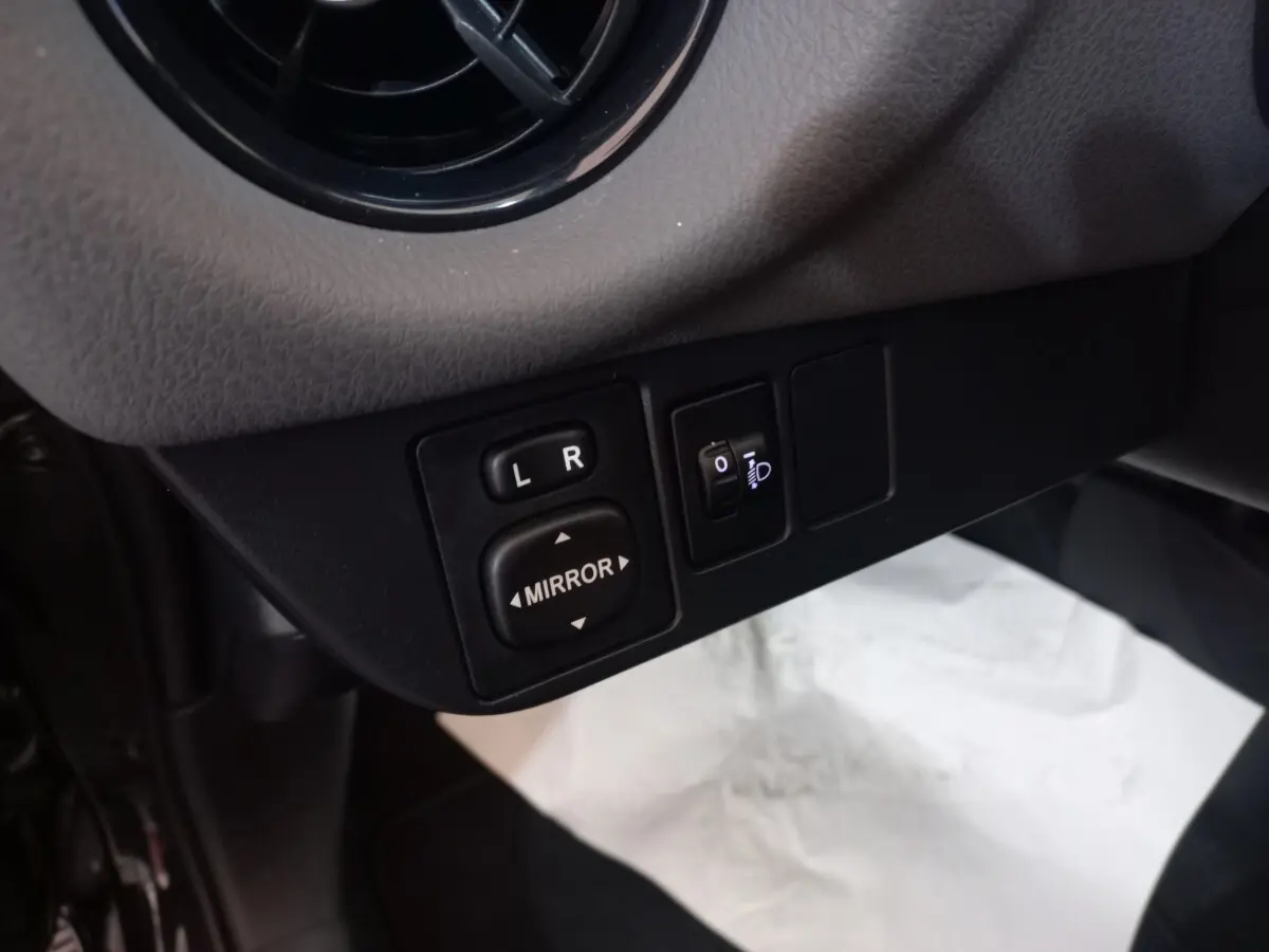 Gros plan sur les commandes de réglage des rétroviseurs côté gauche dans l'habitacle d'une Toyota Yaris noire 2018.