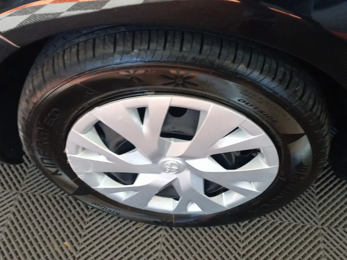 Gros plan sur la roue avant gauche de la Toyota Yaris noire, mettant en valeur la jante en alliage argenté au design moderne.