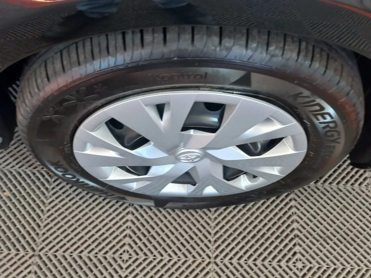 Gros plan sur la roue avant droite d'une Toyota Yaris noire, mettant en valeur la jante argentée et le pneu Hankook.
