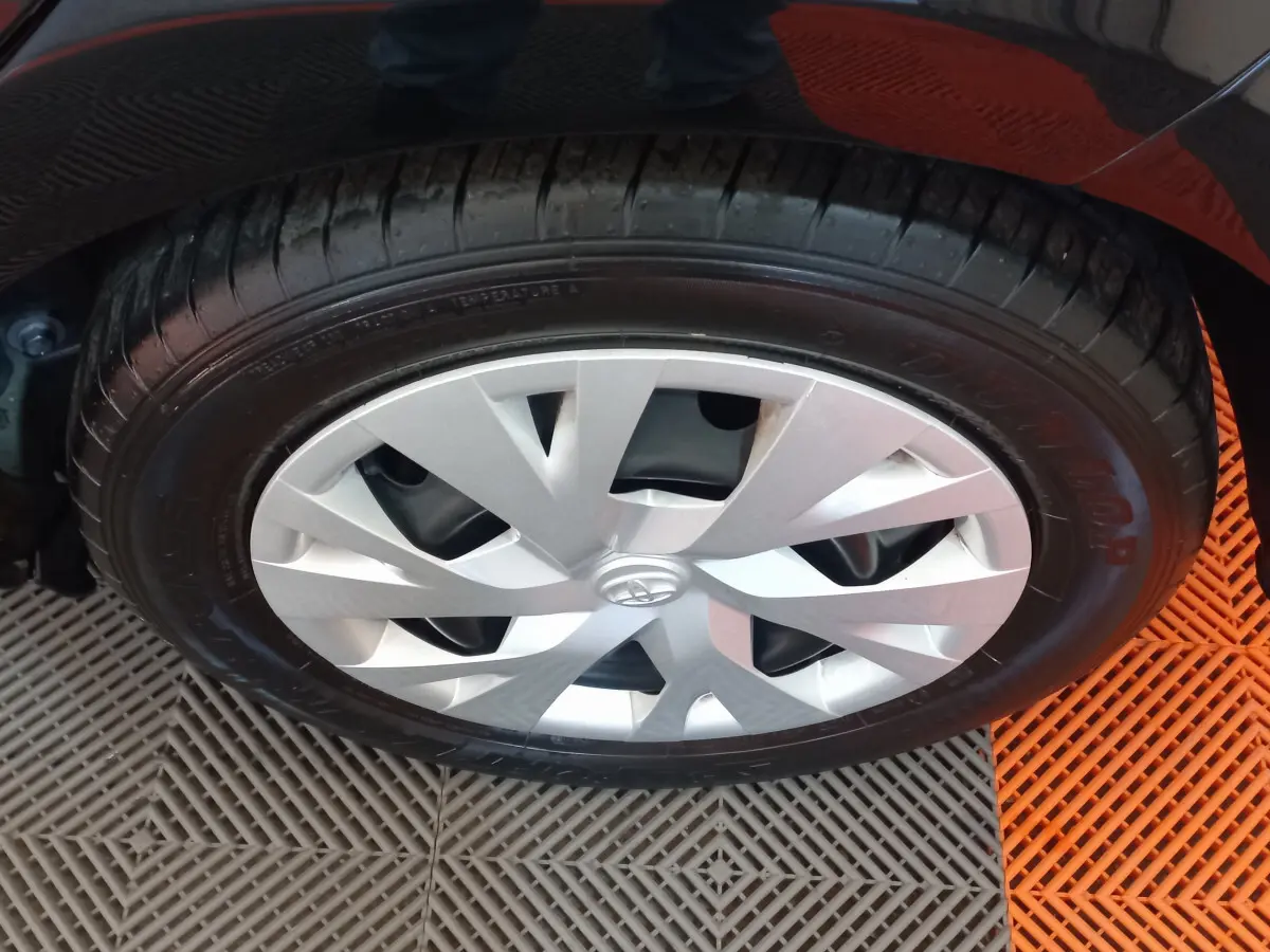 Gros plan sur la roue avant droite noire d'une Toyota Yaris 1.5 Hybrid avec enjoliveur argenté au design moderne.