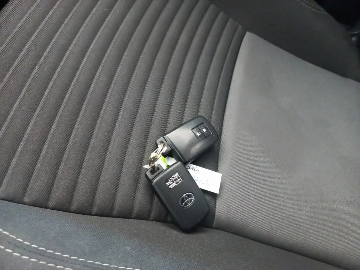 Clé Toyota posée sur la sellerie noire en tissu du siège avant de la Yaris 1.5 VVT-I Hybrid France Business.