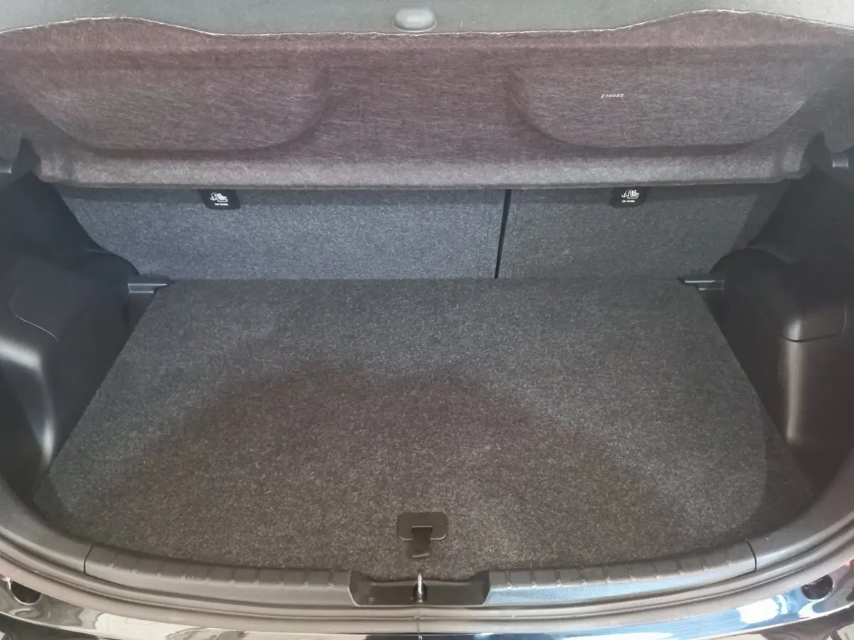 Coffre ouvert vu de l'arrière d'une Toyota Yaris noire, montrant l'espace de chargement et la tablette de séparation.