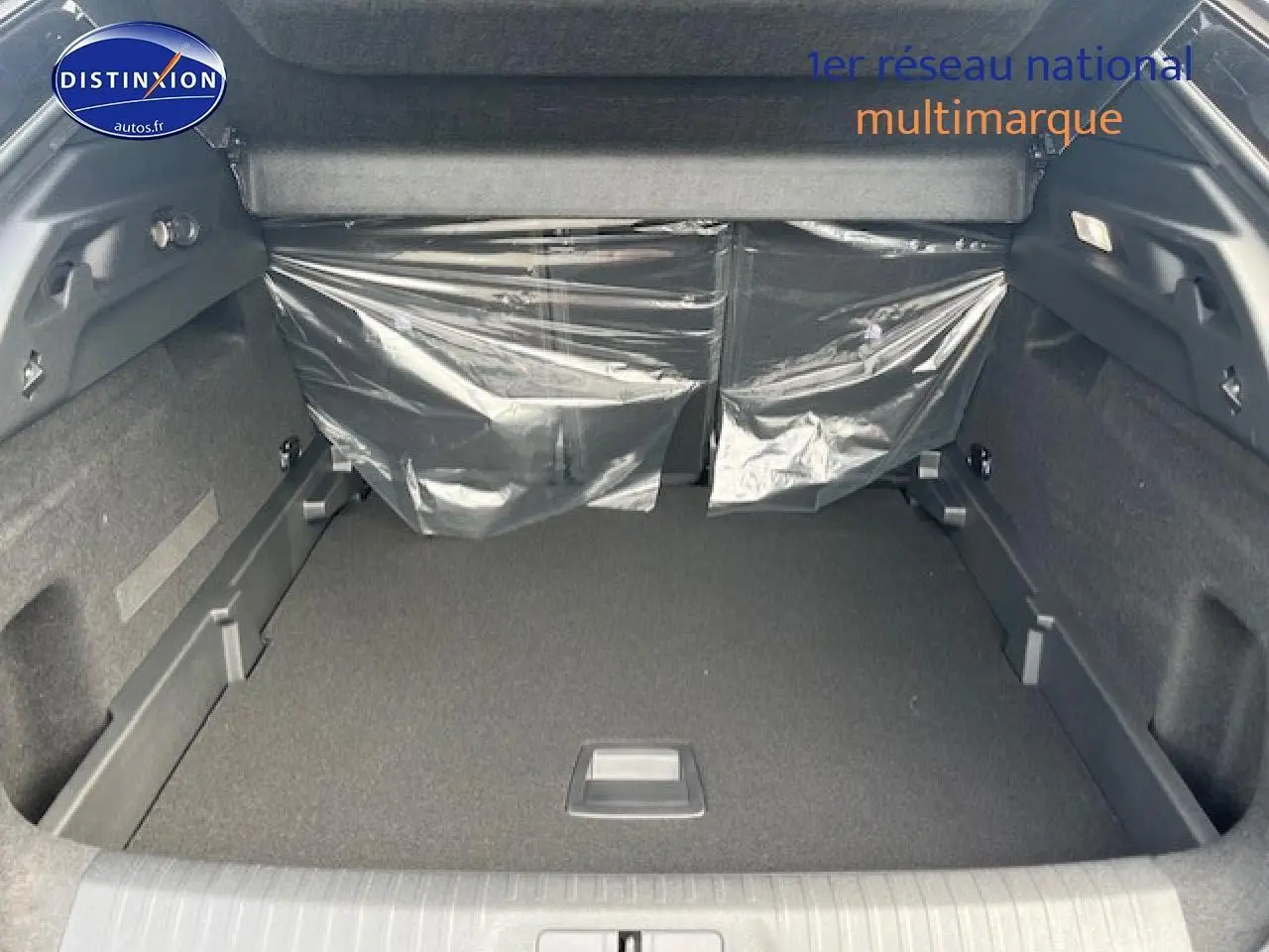 Vue intérieure du coffre spacieux du Peugeot 3008 gris titane, avec banquette arrière protégée par film plastique.