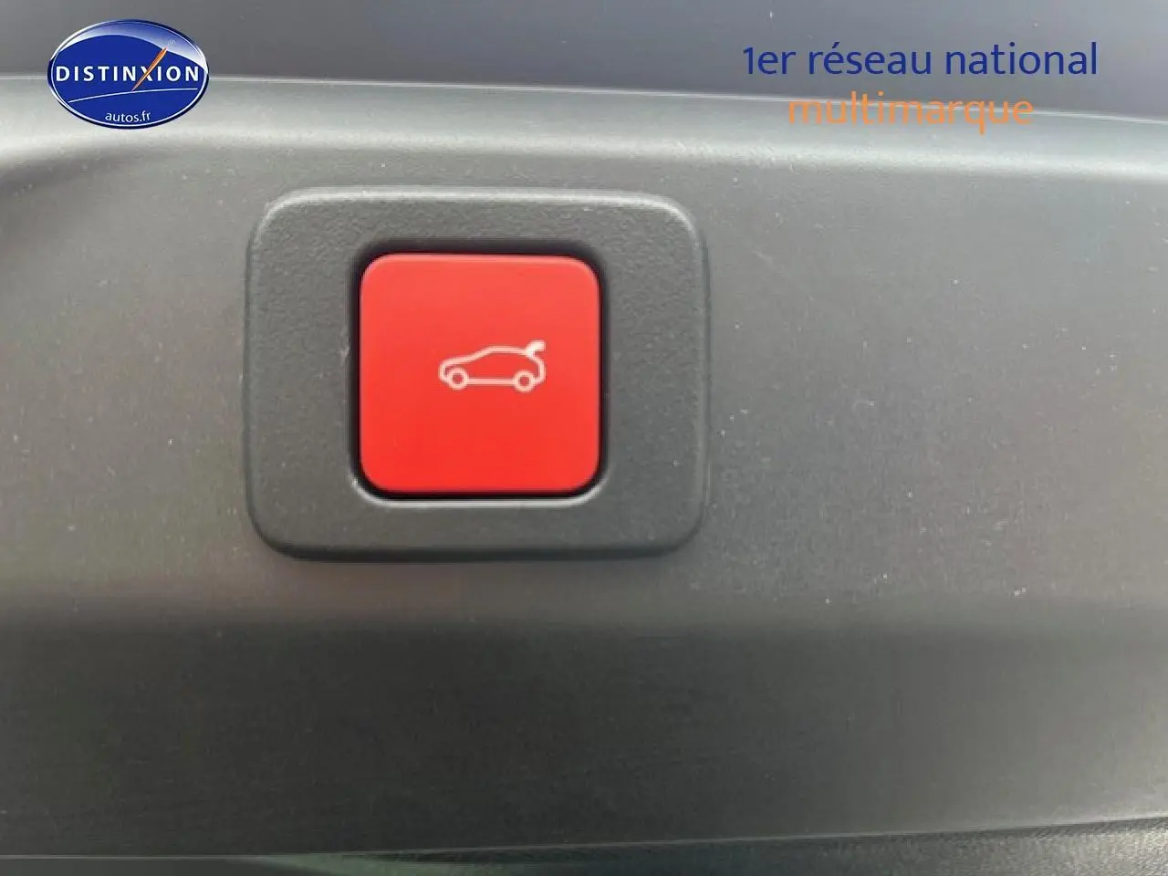Bouton rouge d'ouverture électrique du coffre sur un Peugeot 3008 gris titane, vue en gros plan intérieur.