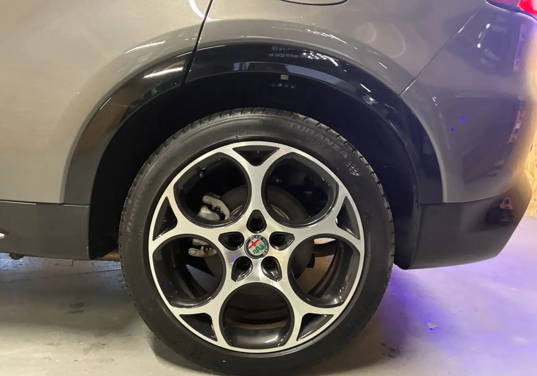 Vue arrière côté droit d'une Alfa Romeo Tonale gris foncé, mettant en valeur l'arche de roue et le feu arrière.