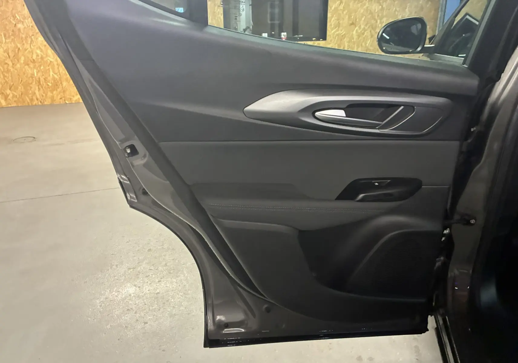 Vue intérieure de la porte arrière droite gris foncé de l'Alfa Romeo Tonale 1.3 PHEV 280 BVA TI avec poignée argentée et panneau noir.