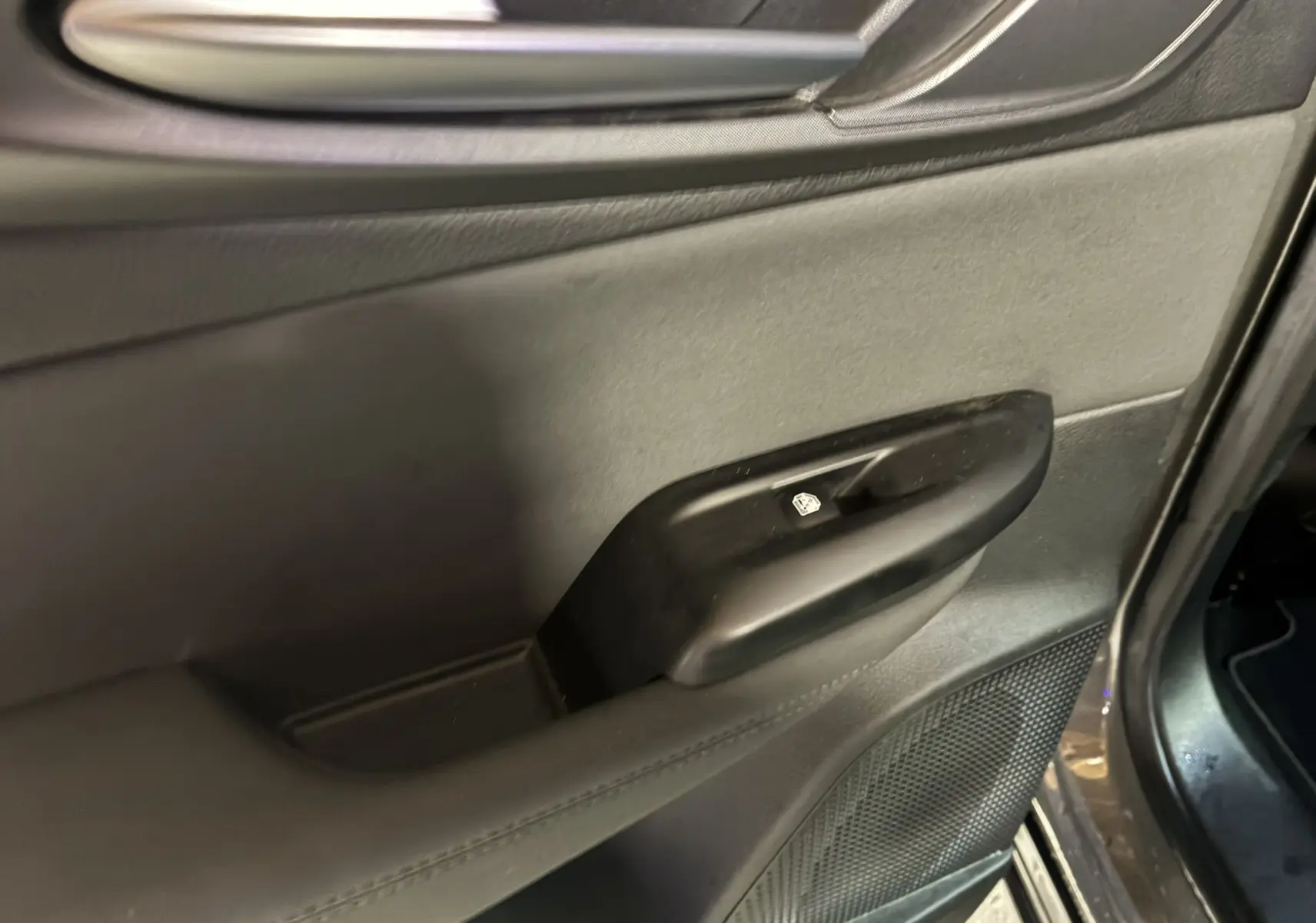Détail de la portière intérieure côté conducteur de l'Alfa Romeo Tonale gris foncé, avec commande de lève-vitre.