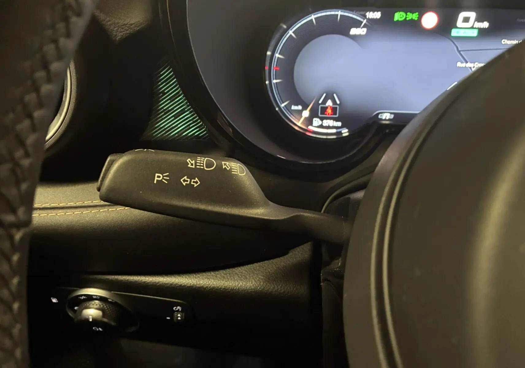 Détail intérieur côté gauche montrant le commodo de clignotants et le tableau de bord numérique de l'Alfa Romeo Tonale gris foncé.