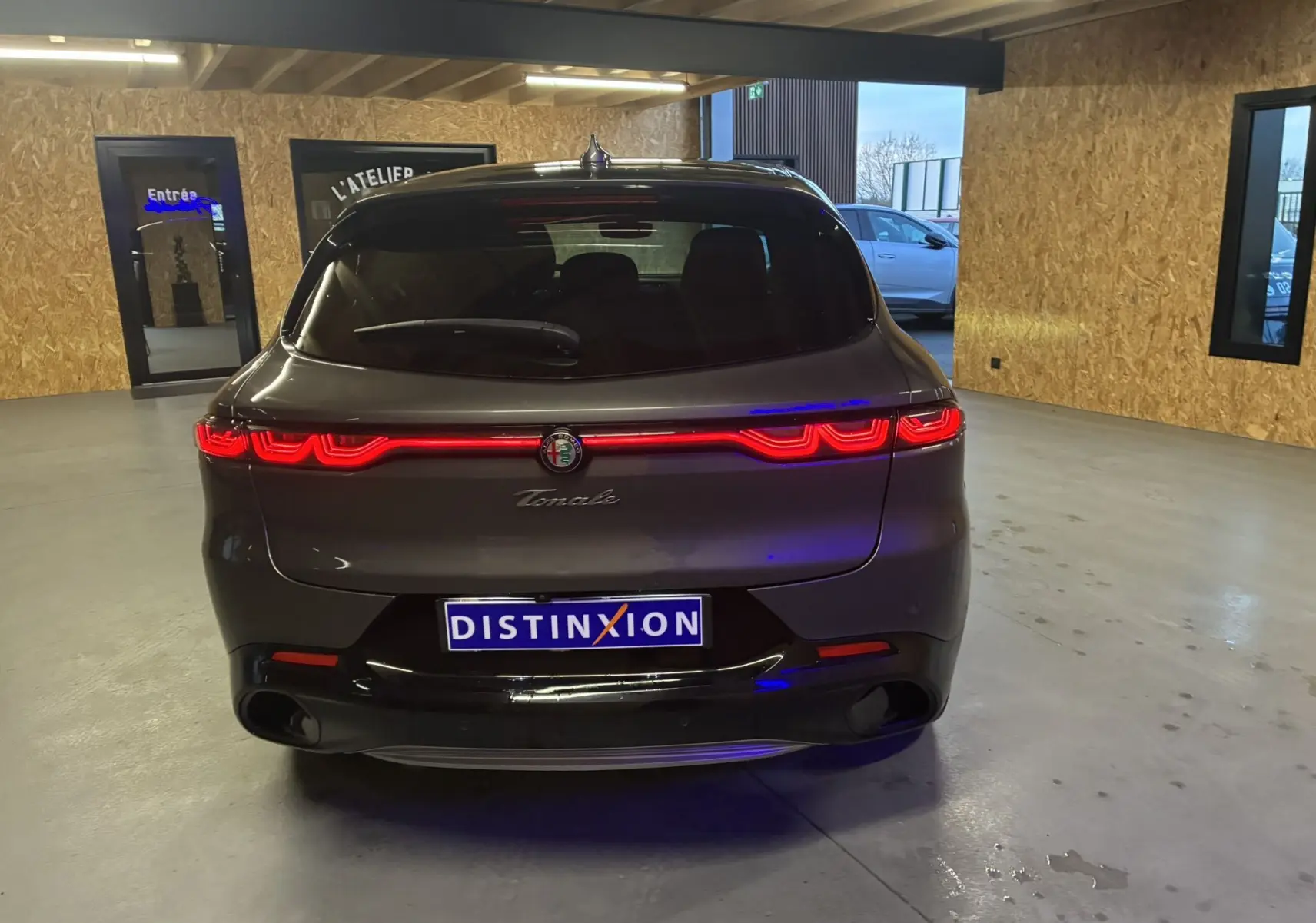 Vue arrière d'une Alfa Romeo Tonale gris foncé 2023 avec feux arrière LED allumés dans un garage.