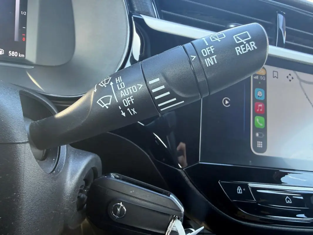 Gros plan sur la commande d’essuie-glace et le tableau de bord numérique d’une Opel Corsa rouge 2025, intérieur noir brillant.