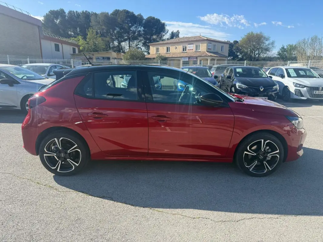 Opel Corsa 2025 rouge vue de profil côté gauche, avec jantes alliage noires et toit noir contrasté.