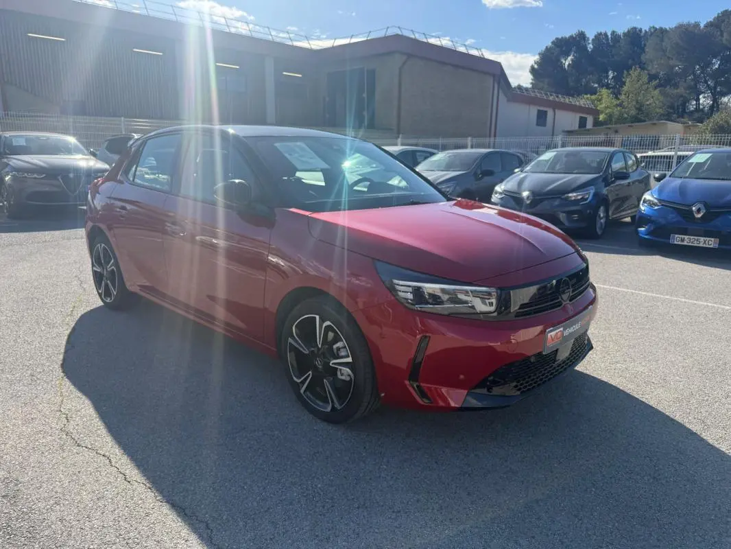 Opel Corsa 2025 rouge vue 3/4 avant droit, avec jantes noires et calandre moderne brillante.
