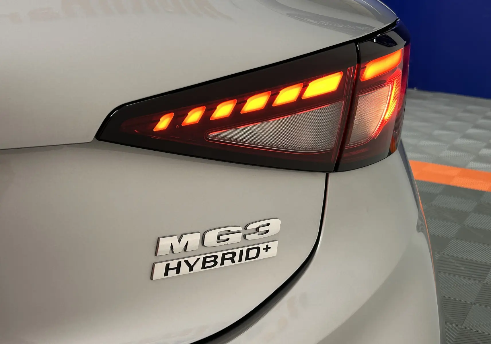 Gros plan sur le feu arrière droit rouge allumé et le logo MG3 Hybrid+ d'une MG3 Cosmic Silver.