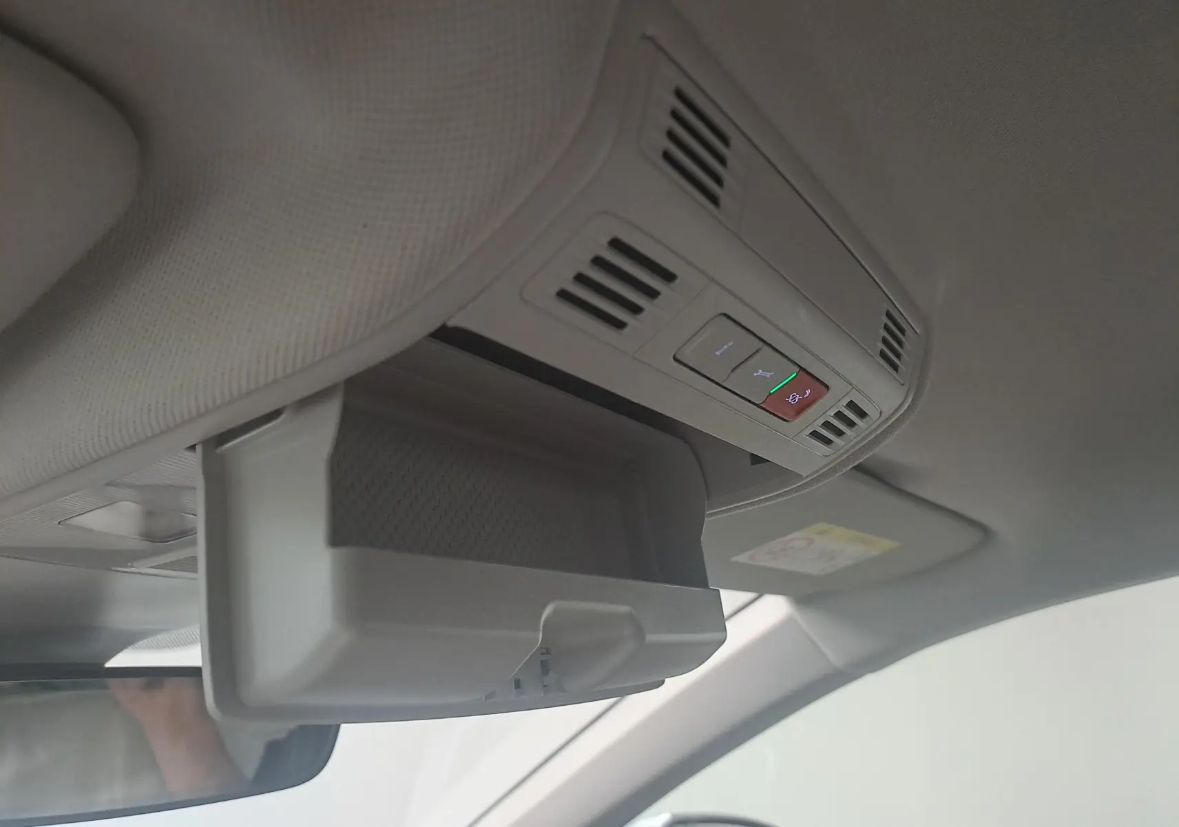 Vue intérieure du plafond avant côté conducteur d'une Volkswagen Polo argent avec compartiment lunettes ouvert et commandes intégrées.