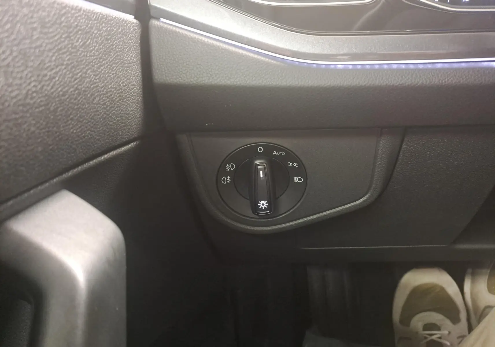 Gros plan sur le bouton de commande des phares dans l'habitacle noir du Volkswagen Polo 2025 côté gauche.