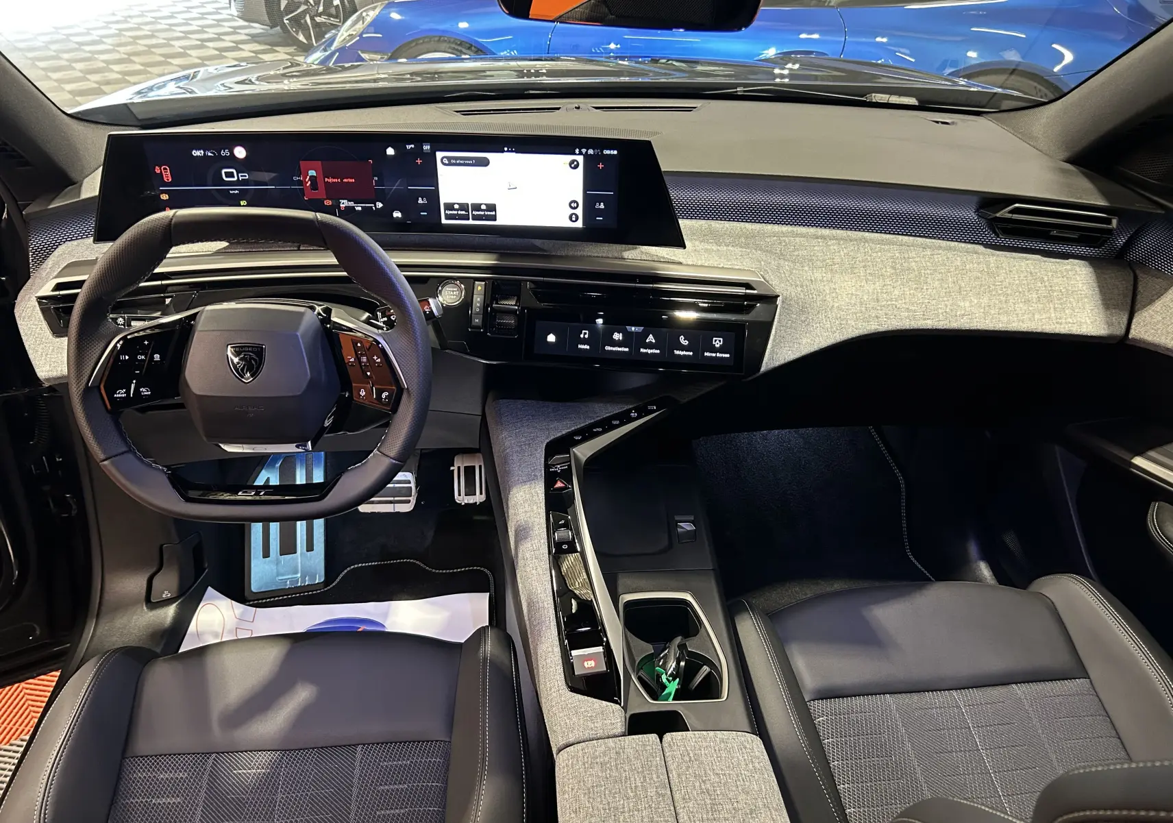 Vue intérieure avant du Peugeot 5008 Hybrid gris titane, mettant en valeur le tableau de bord numérique et le volant compact multifonction.