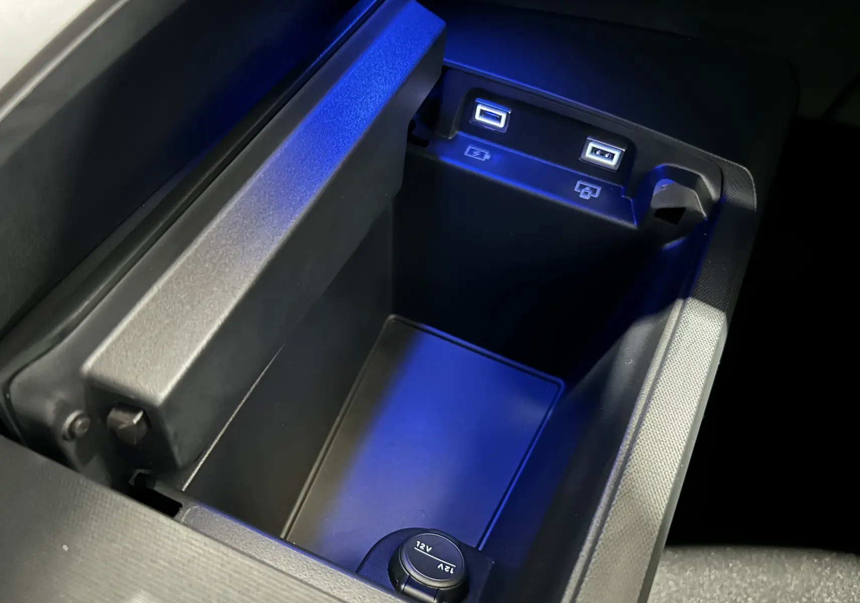 Vue rapprochée de la console centrale noire avec prises USB et prise 12V du Peugeot 5008 Hybrid gris titane.