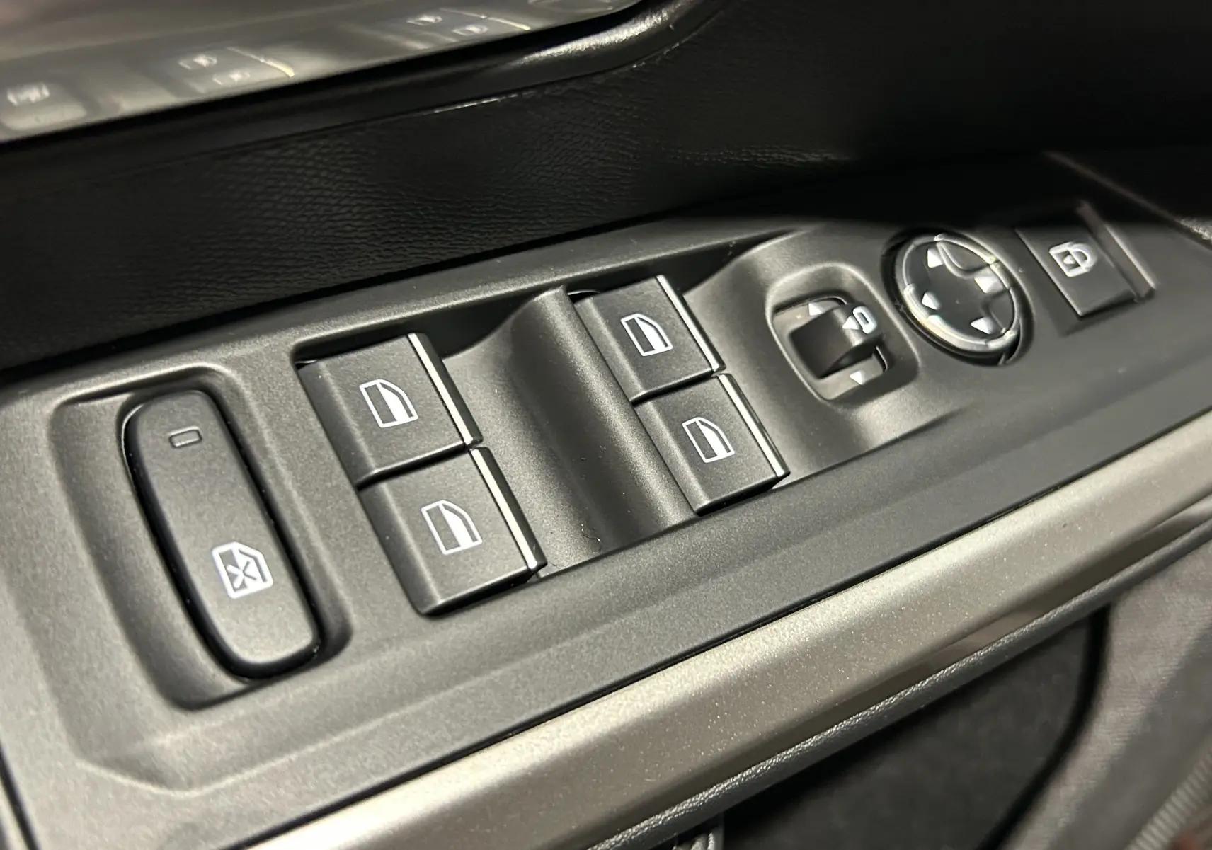 Gros plan sur les commandes électriques des vitres et rétroviseurs côté conducteur du Peugeot 5008 gris titane.