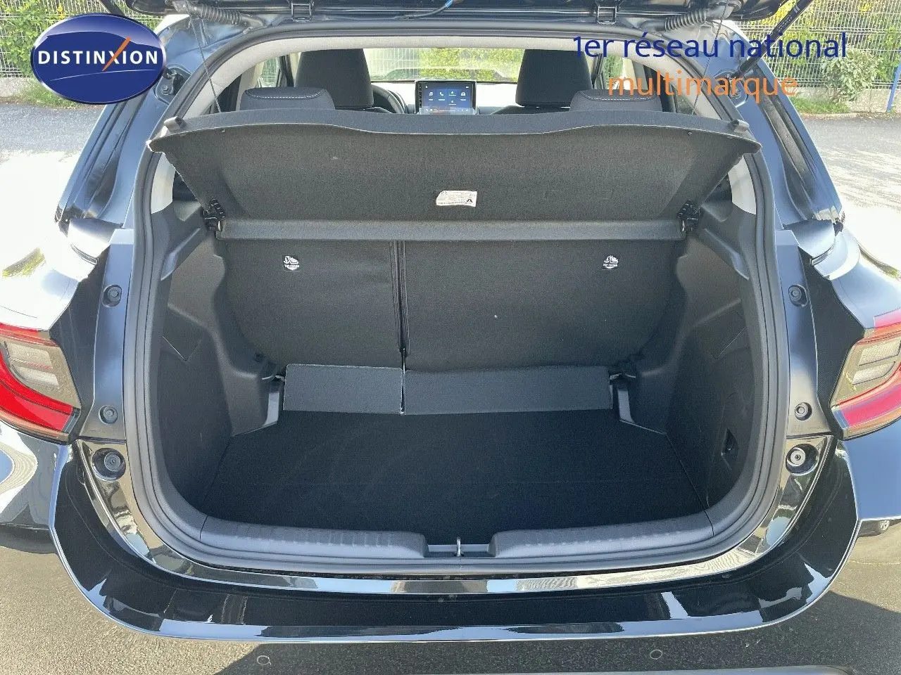 Coffre ouvert en vue arrière d'une Toyota Yaris Hybrid 116ch noir métal, montrant l'espace de chargement vide.