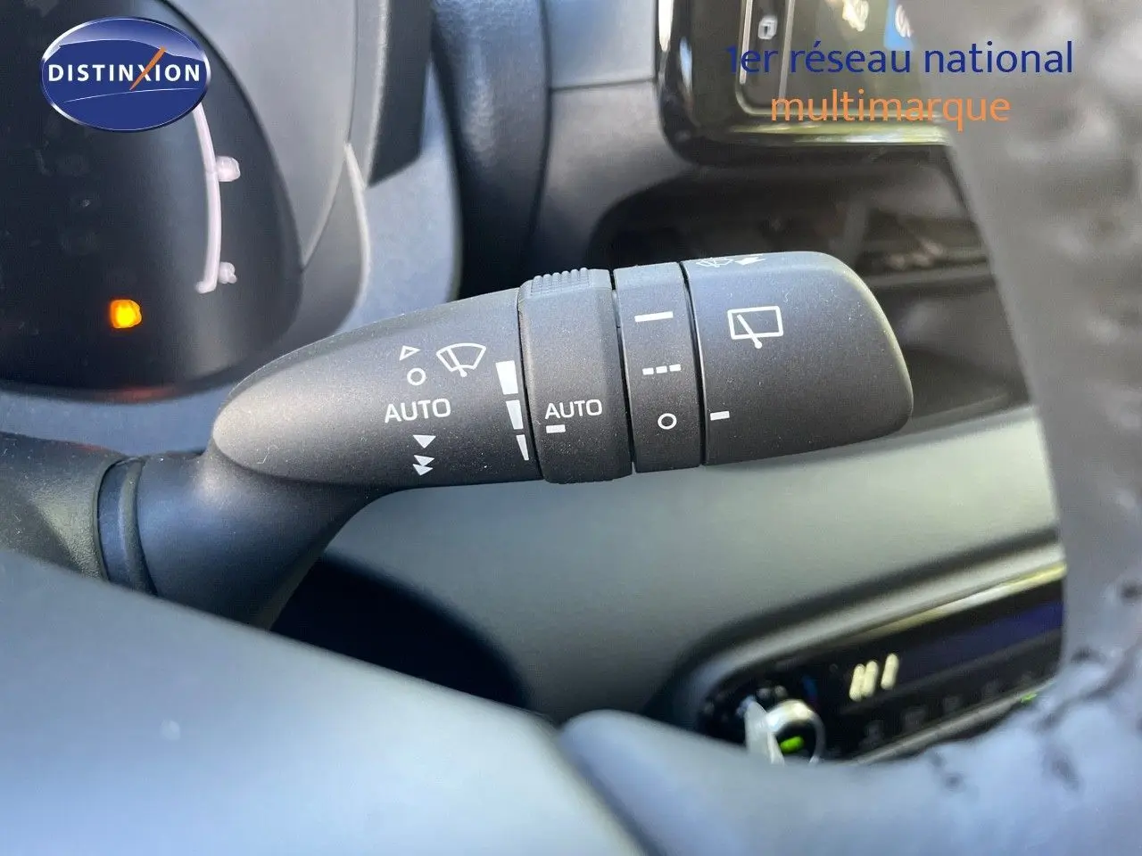 Gros plan sur la commande d'essuie-glace automatique à gauche du volant d'une Toyota Yaris Hybrid 2025 noire.