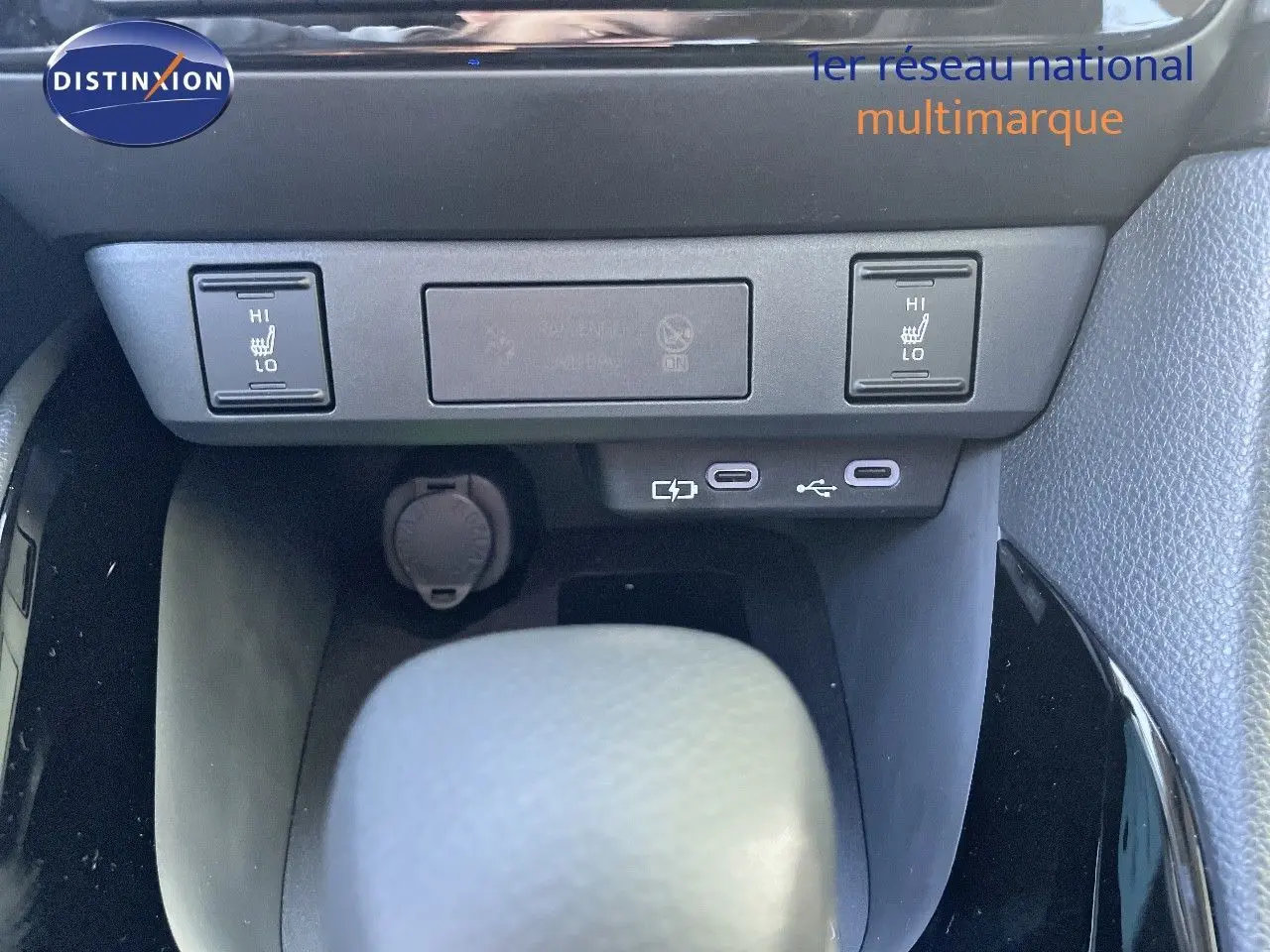 Gros plan sur la console centrale de la Toyota Yaris Hybrid 2025, montrant les commandes de siège chauffant et ports USB.
