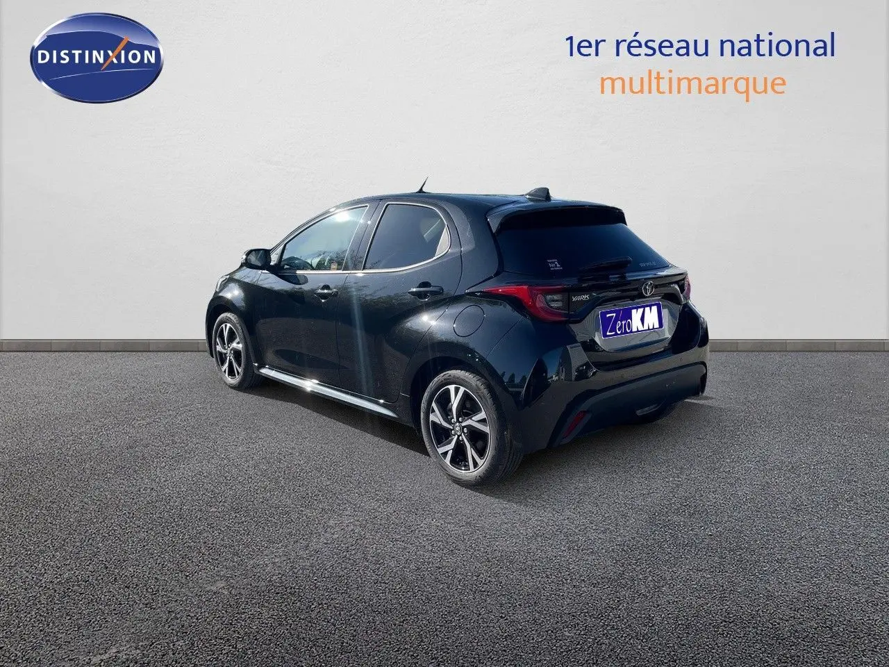 Toyota Yaris Hybrid noir métal vue 3/4 arrière côté gauche avec jantes bi-ton et feux LED distinctifs.
