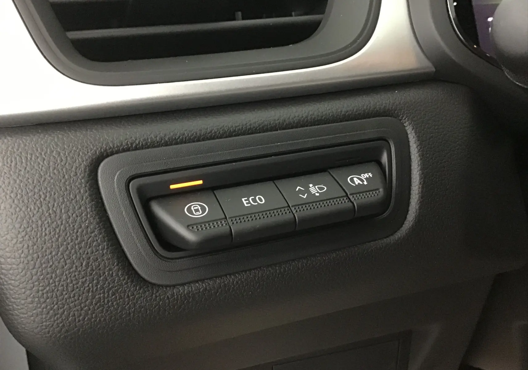 Panneau de commandes intérieur du Renault Captur 2025, boutons ECO et réglage des phares avec témoin orange allumé.