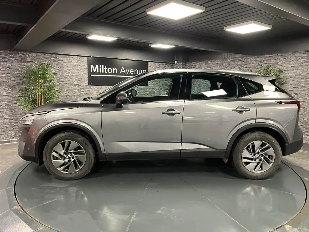 Profil côté gauche d'un Nissan Qashqai gris 2023 en showroom, soulignant ses lignes modernes et jantes alliage 17 pouces.