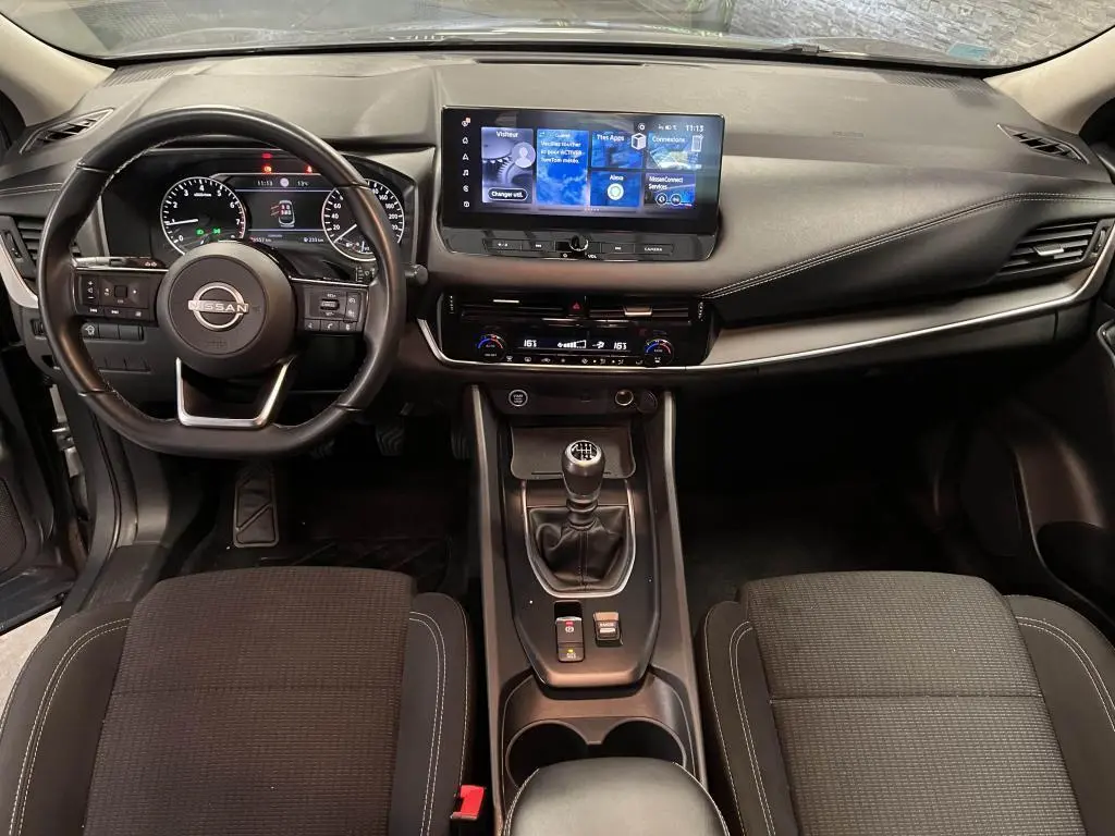 Intérieur noir du Nissan Qashqai 2023, vue frontale sur le tableau de bord avec écran tactile et levier de vitesses manuel.