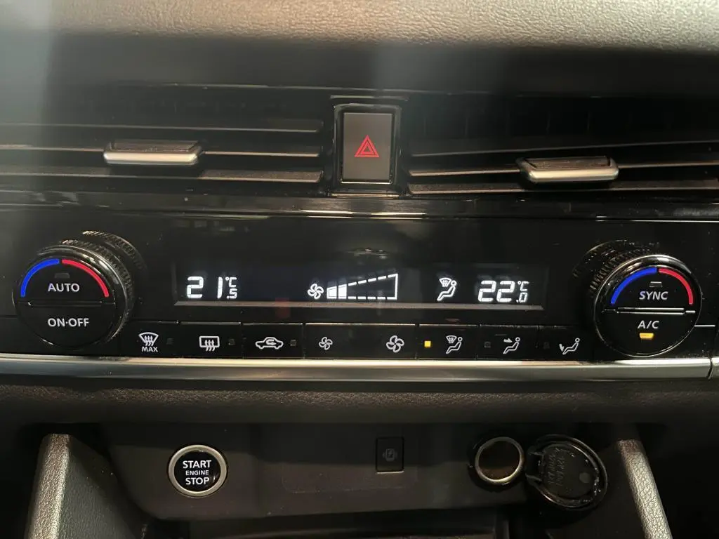 Vue rapprochée de la console centrale du Nissan Qashqai gris 2023, affichant la climatisation automatique bi-zone et le bouton Start/Stop.