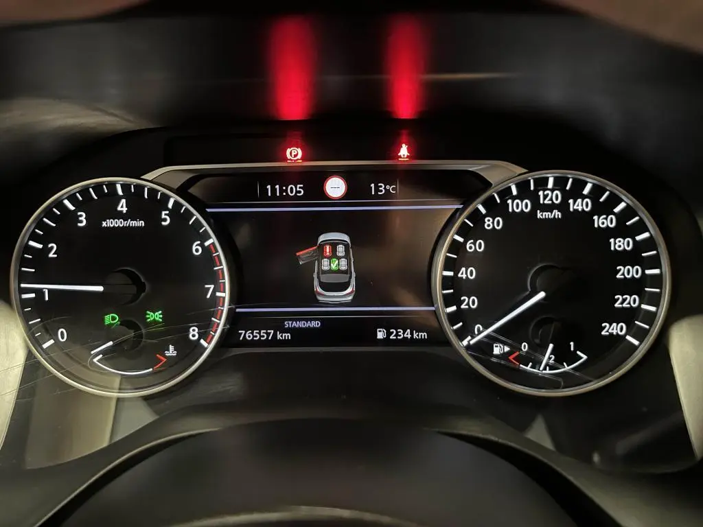 Tableau de bord du Nissan Qashqai 2023 montrant compte-tours, vitesse, et écran central avec alertes et kilométrage.
