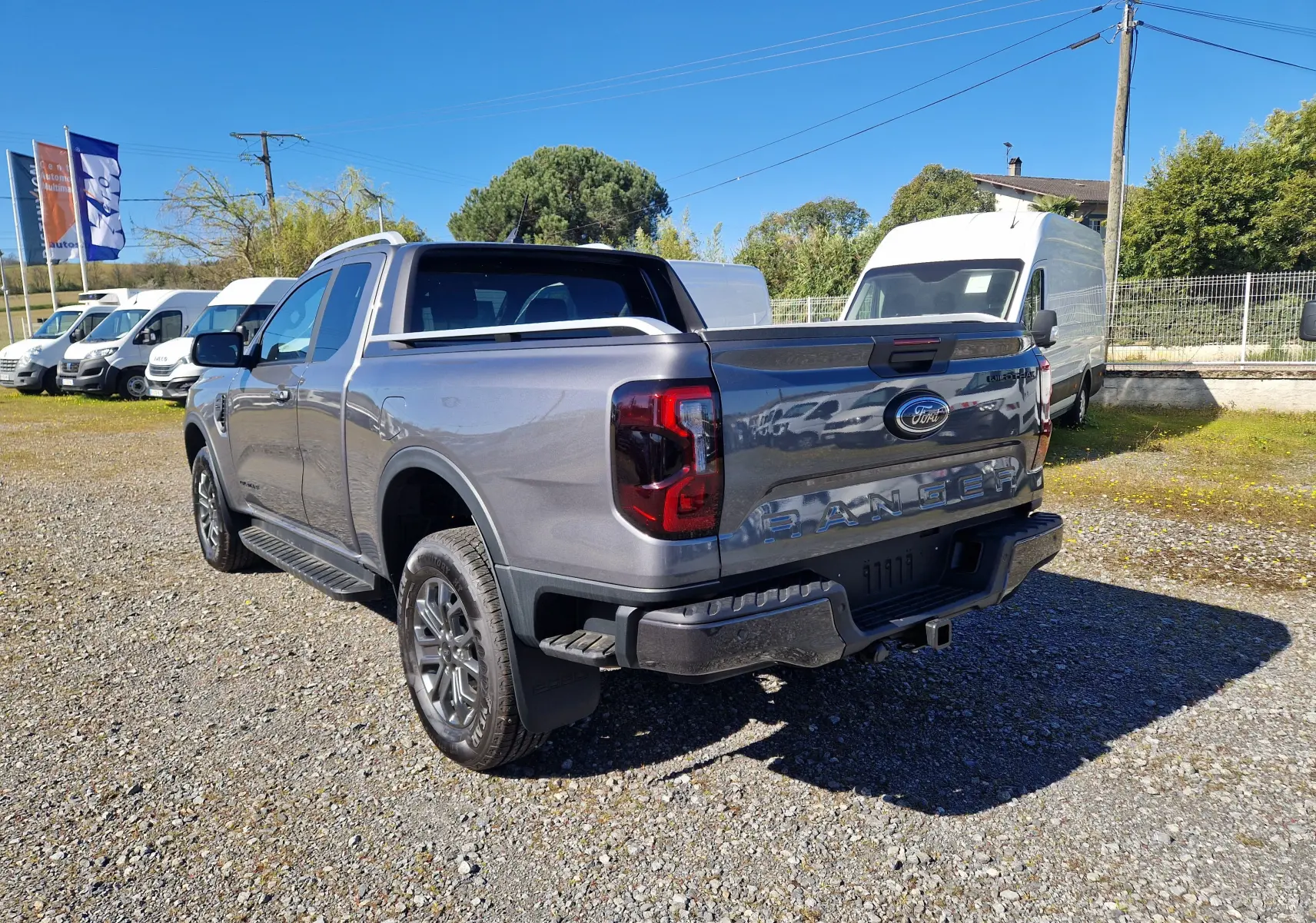 Vue 3/4 arrière droite d'un Ford Ranger Super Cabine gris carbone avec benne et feux arrière LED distinctifs.