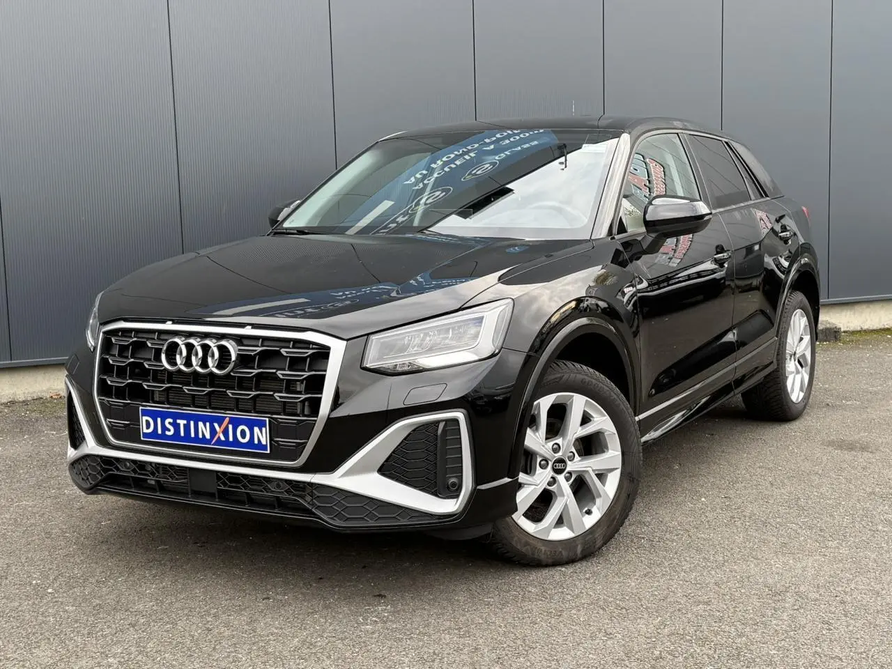 Audi Q2 noir métallisé en vue 3/4 avant droit, mettant en valeur sa calandre distinctive et ses jantes S line.