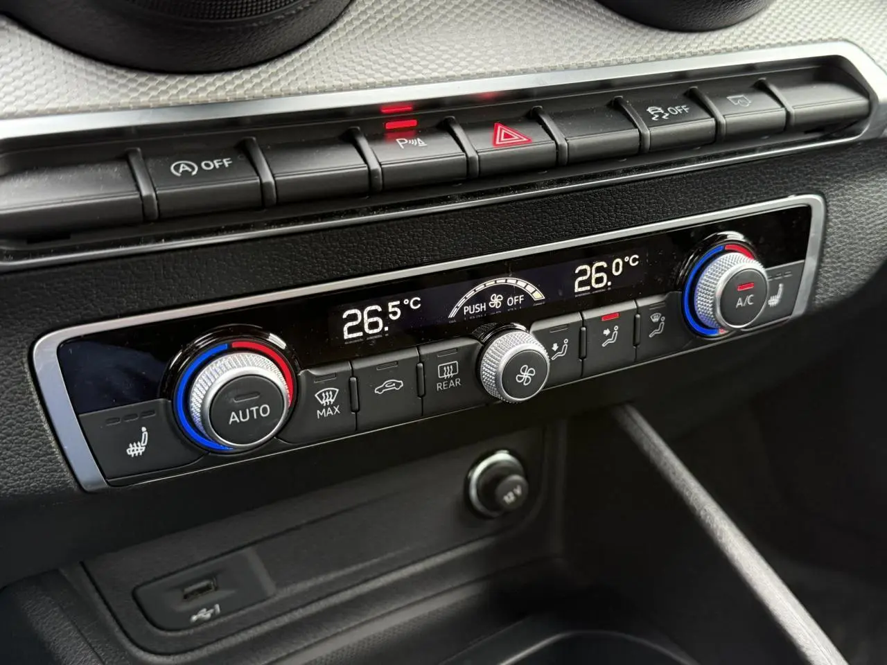 Gros plan sur la console de climatisation de l'Audi Q2 2023, avec réglages numériques et boutons de contrôle noirs.