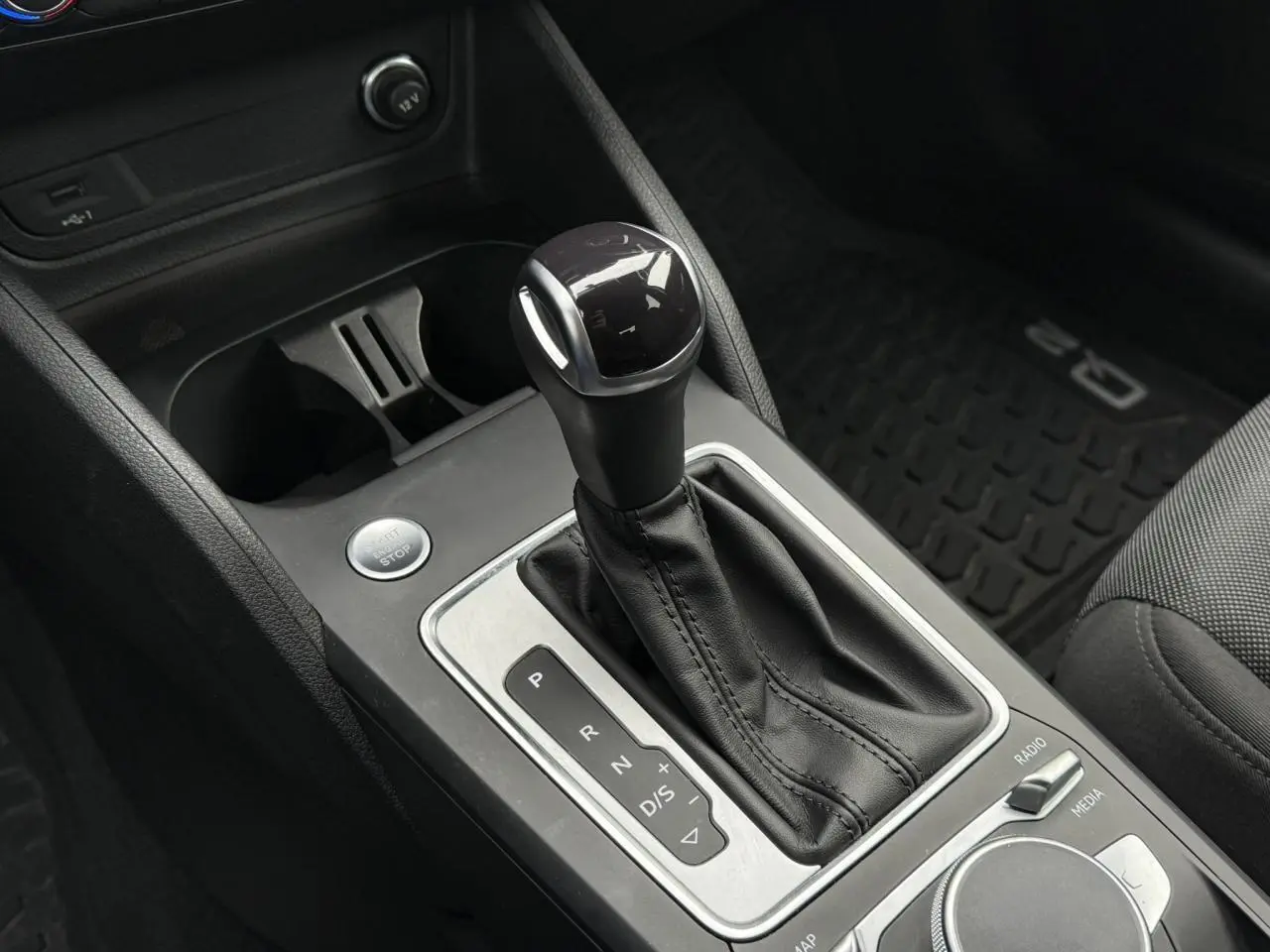 Le levier de vitesse automatique noir et argenté de l'Audi Q2 2023, avec bouton start/stop et console centrale visible.