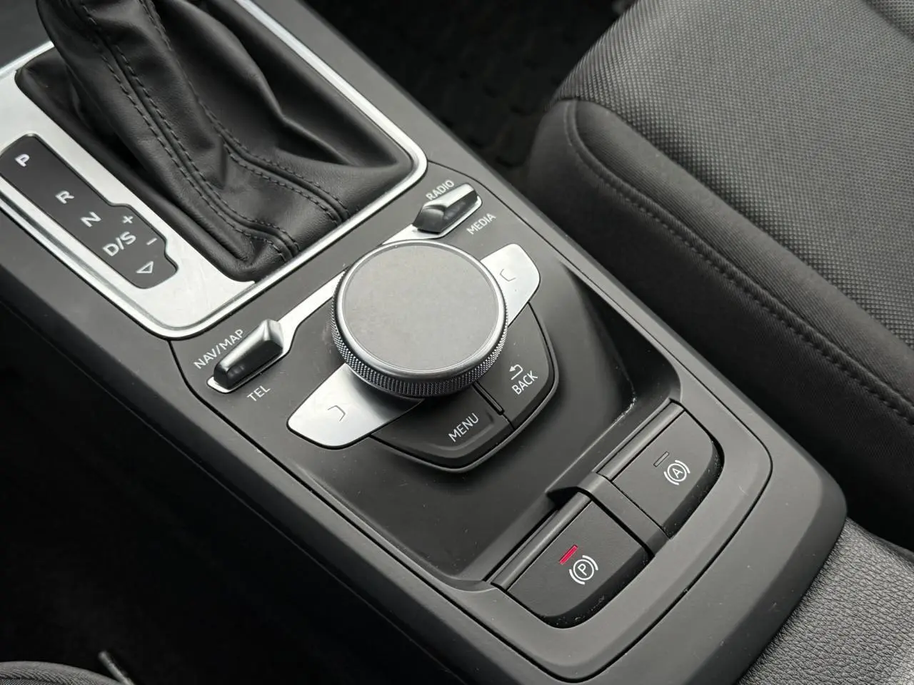 Gros plan sur la console centrale noire de l'Audi Q2 2023, montrant la commande de boîte auto et les boutons électroniques.