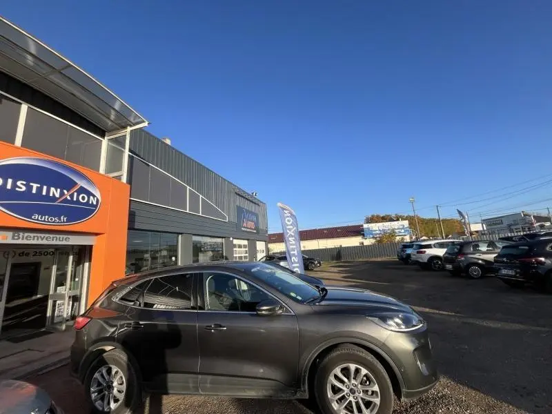 Ford Kuga 2.0 EcoBlue gris Magnetic métallisé, vue de profil côté gauche devant un concessionnaire.