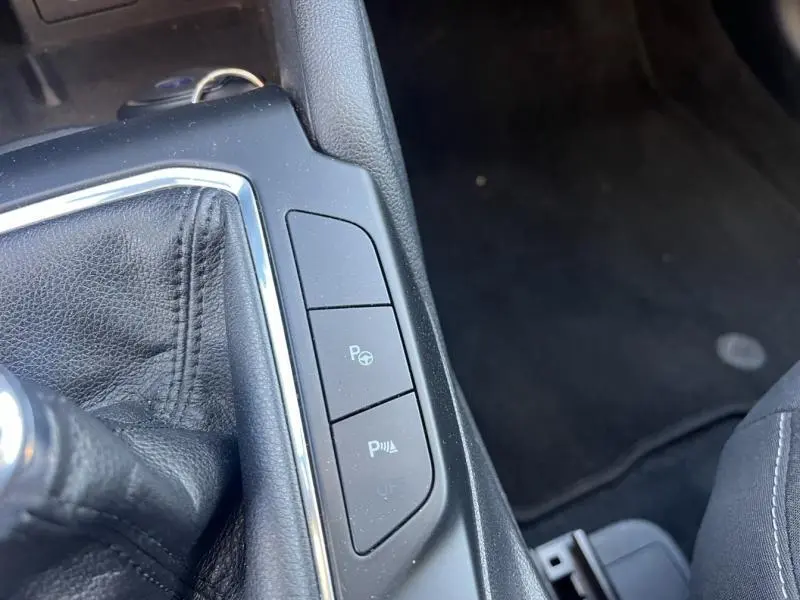 Vue rapprochée de la console centrale noire du Ford Kuga 2021 avec boutons de contrôle du stationnement et levier de vitesse cuir.
